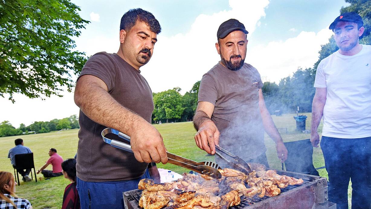 Khaled Kassem (Mitte) hat jede Menge Hähnchenfleisch auf den Grill gelegt. Beim Treffen mit der Großfamilie auf dem öffentlichen Platz an den Heeper Fichten an diesem Sonntag gedenkt er auch seiner kürzlich im Irak verstorbenen Mutter. | © Barbara Franke