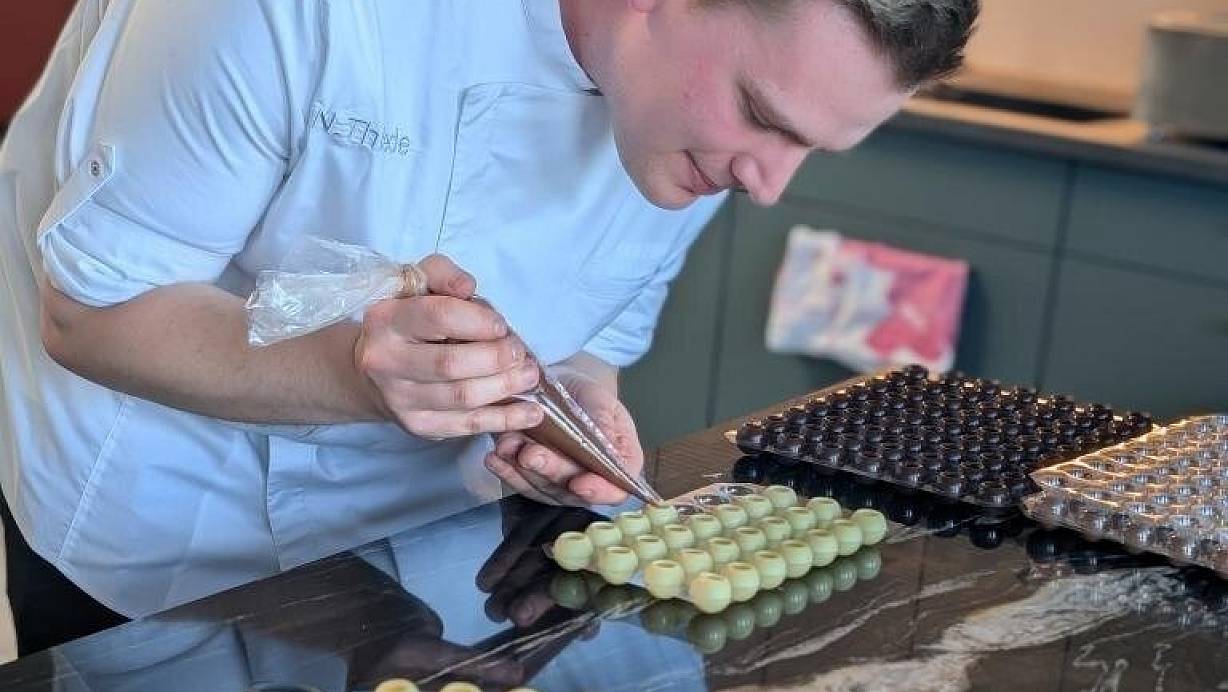 Nils Thiede aus dem Kreis Gütersloh füllt eine Ganache in die weißen Pralinen. Er liebt das Handwerkliche an seinem Beruf. "Man sieht, was man hergestellt hat und kann es vernaschen", sagt der 25-Jährige. | © Privat