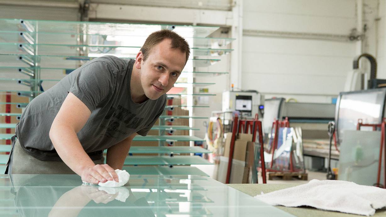 Schaut immer ganz genau hin: Bevor Daniel Rahe diese fertig gestrahlte und gebohrte Ganzglastür versiegelt, überprüft er jedes Detail. Selbst kleinste Material- oder Produktionsfehler entgehen ihm nur selten. | © Foto: Lebenshilfe