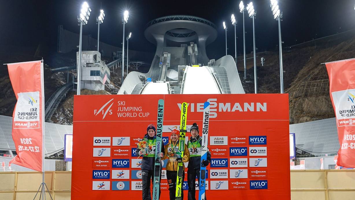 Katharina Schmid (M) bejubelt ihren Sieg auf der Olympia-Anlage. | © Wu Diansen/XinHua/dpa