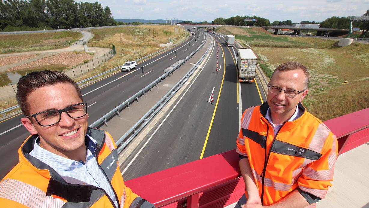 Projektleiter Florian Fawick (l.) und Bauabteilungsleiter Tobias Fischer von Stra&szlig;en NRW im L&ouml;hner Kreuz, dem letzten Bauabschnitt der Nordumgehung. Hinter ihnen ist noch die Baustellenf&uuml;hrung auf der neuen Autobahn mit den gelben Fahrbahnmarkierungen zu sehen. | &copy; J&ouml;rg Stuke