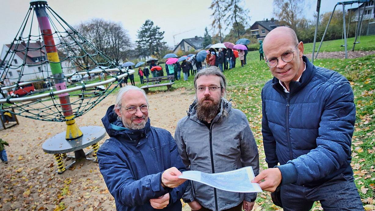 Bezirksbürgermeister Jesco von Kuczkowski (l.) und Sozialdezernent Ingo Nürnberger (r.) zeigten Martin Meier (Mitte), Initiator der Petition zum Erhalt der Fläche an der Heuberger Straße, wo genau die Kita hinkommen soll. Trotz Regen kamen etwa 50 Nachbarn, um Kritik zu äußern und Alternativen zu diskutieren. | © Barbara Franke