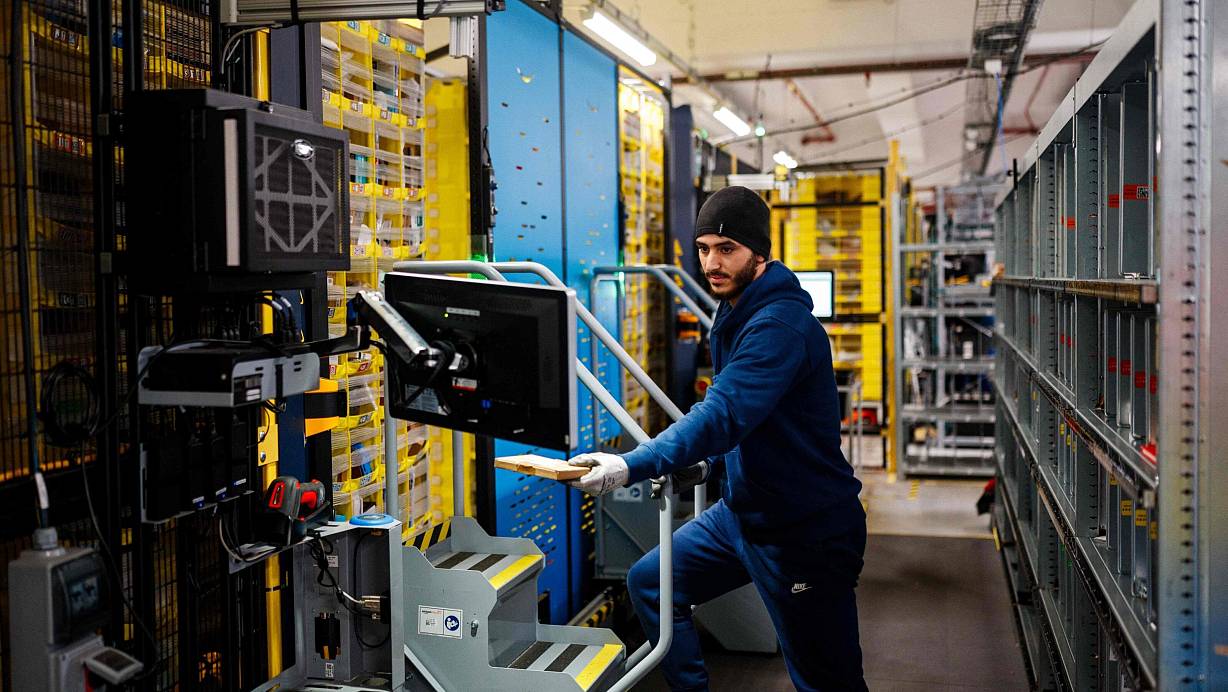 Ein Mitarbeiter kümmert sich um Pakete an einem Logistikstandort von Amazon. | © AFP or licensors