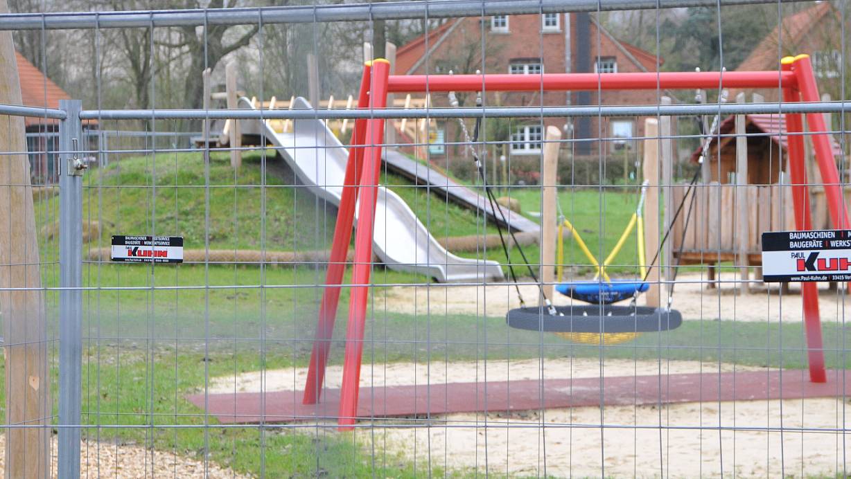 Mit Bauzäunen ist der neue Spielplatz in der Niehaussiedlung abgesperrt. Dahinter locken Vogelnestschaukel und Rutsche. | © Frank Jasper