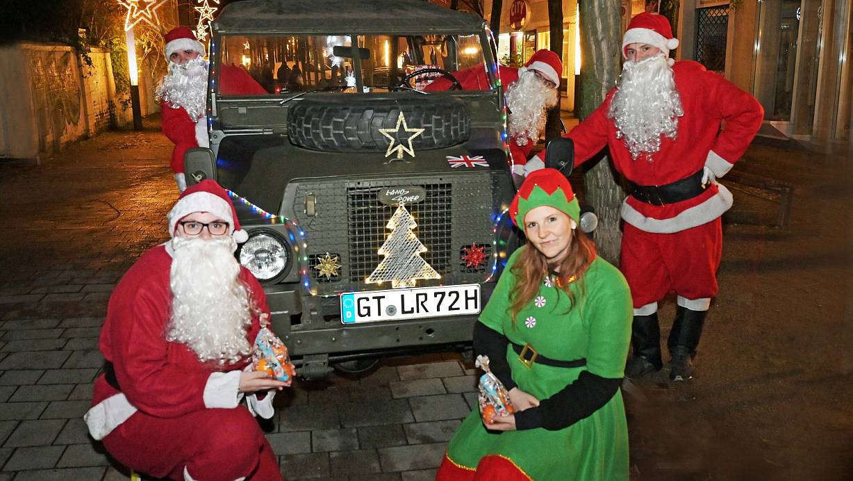 Nadine Marie Rosenberg (v.l), Jörg Steinbrecher, Daniel Sürig und Felix Larsch haben sich als Weihnachtsmäner verkleidet, Leonie Freihof ist eine Weihnachts-Elfe. Mit dem dekorierten, 50 Jahre alten Land Rover Jeep in der Stadt untertwegs. | © Waltraud Leskovsek