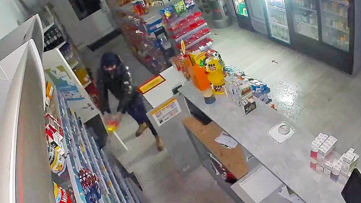 Auf dem Überwachungsvideo ist zu sehen, wie ein vermummter Mann eine Flüssigkeit - vermutlich Brandbeschleuniger - verspritzt. | © Polizei/Screenshot