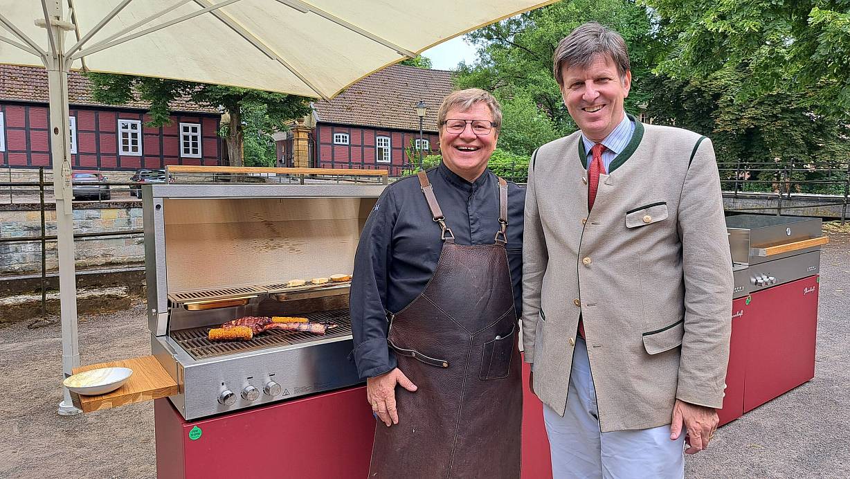 Sven Schurig (l.) und Maximilian Fürst zu Bentheim-Tecklenburg mit Maiskolben und einem Rib-Eye Steak auf dem Grill. | © Marion Pokorra