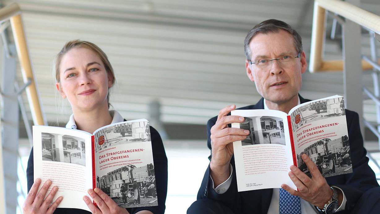 Informative Lektüre: Autorin Karina Isernhinke und Landrat Sven-Georg Adenauer mit dem 13 Band aus der Reihe Veröffentlichungen aus dem Kreisarchiv. | © Foto: Kreis Gütersloh