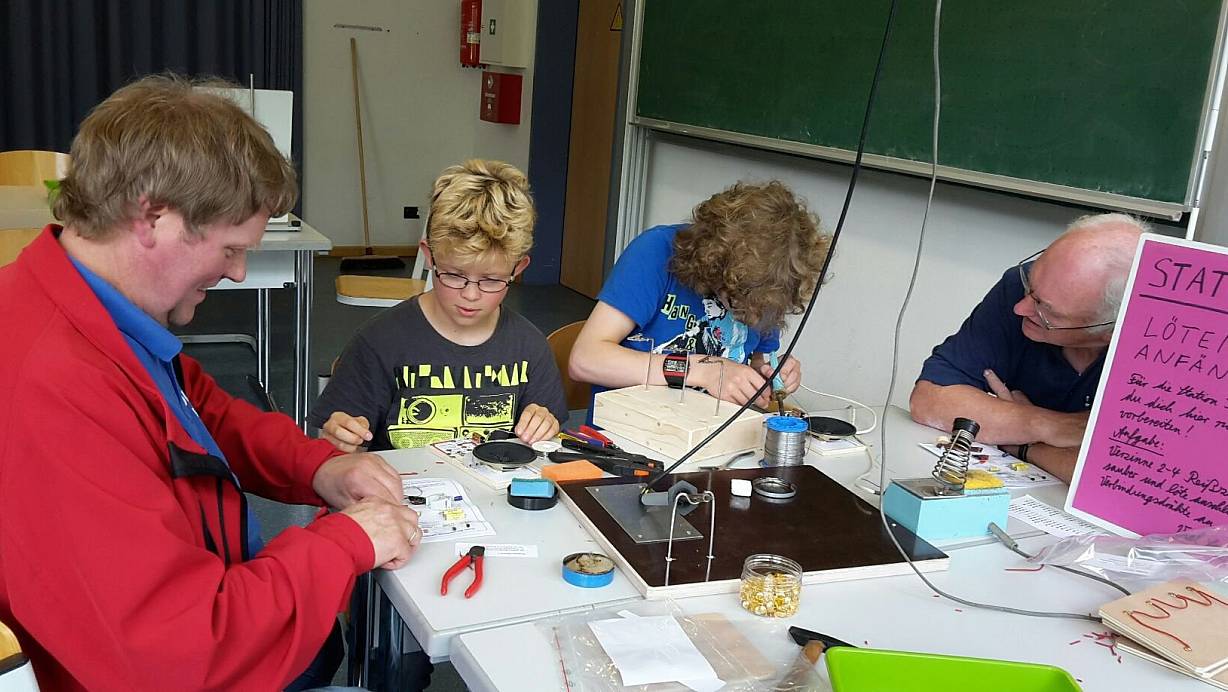 Mit Interesse dabei: Mathis Kuge und Mika Kuge löten eine Schaltung, unterstützt von Wilhelm Lüking und Jürgen Kleffmann. Der Verein "Zetis" will genau für solche Arbeiten Interesse bei Kindern und Jugendlichen wecken. | © Zetis