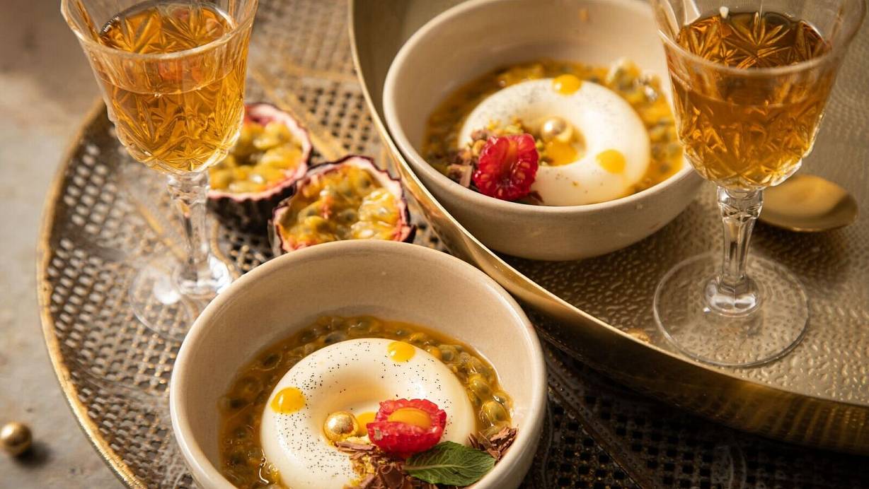 Panna Cotta mit Passionsfrucht, Himbeere, Mangotupfer, Minze, Pistazie, Schokolade und goldenen Schokokugeln in Savarin-Form zubereitet. Das ist eine Backform in flacher, ringförmiger Gestalt. | © Christin Klose/dpa-tmn