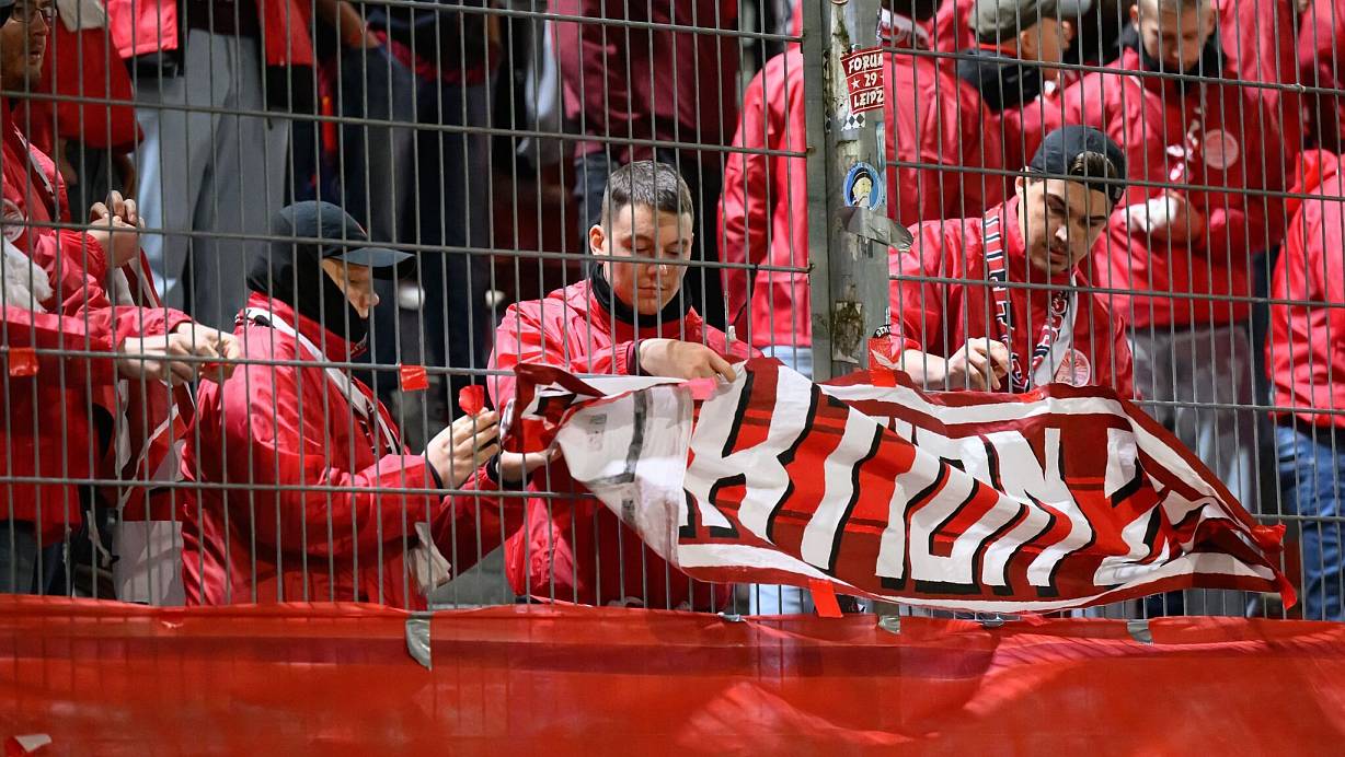 Leipzigs Fans nehmen zu Beginn der zweiten Halbzeit die Fahnen ab. Vor Beginn des Spiels war ein Fan vor dem Stadion verstorben. | © Robert Michael/dpa