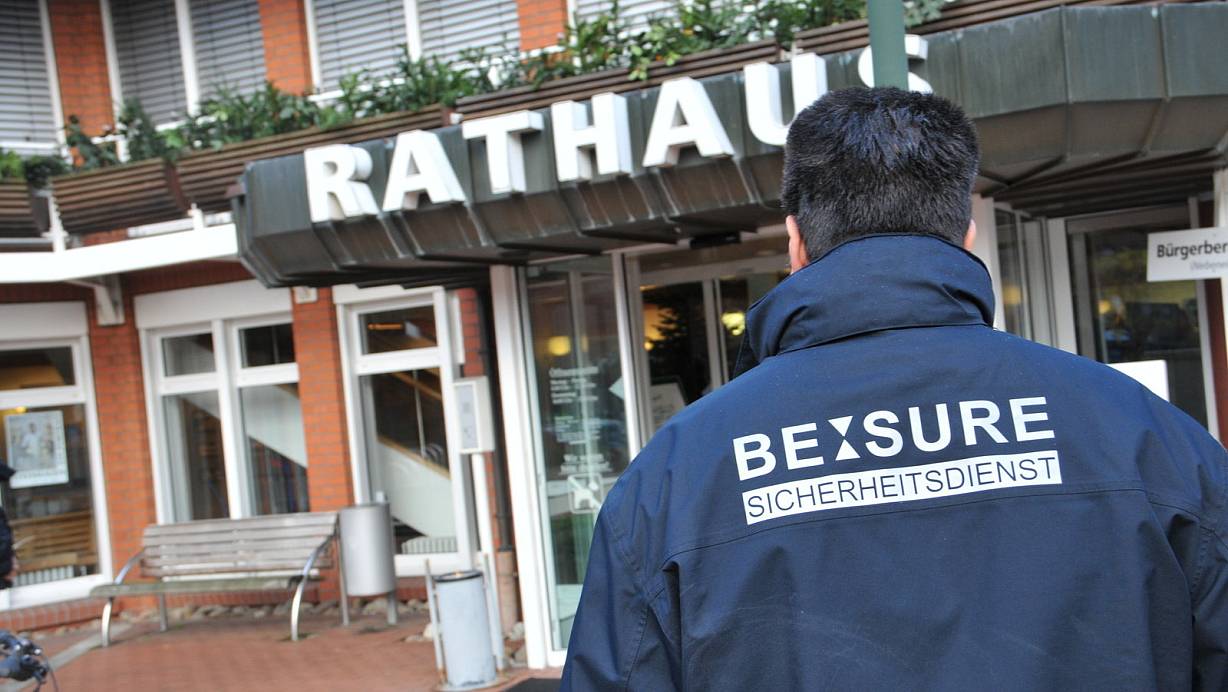 Mitarbeiter eines Sicherheitsdienstes bewachen den Rathaus-Haupteingang in Steinhagen. | © Frank Jasper
