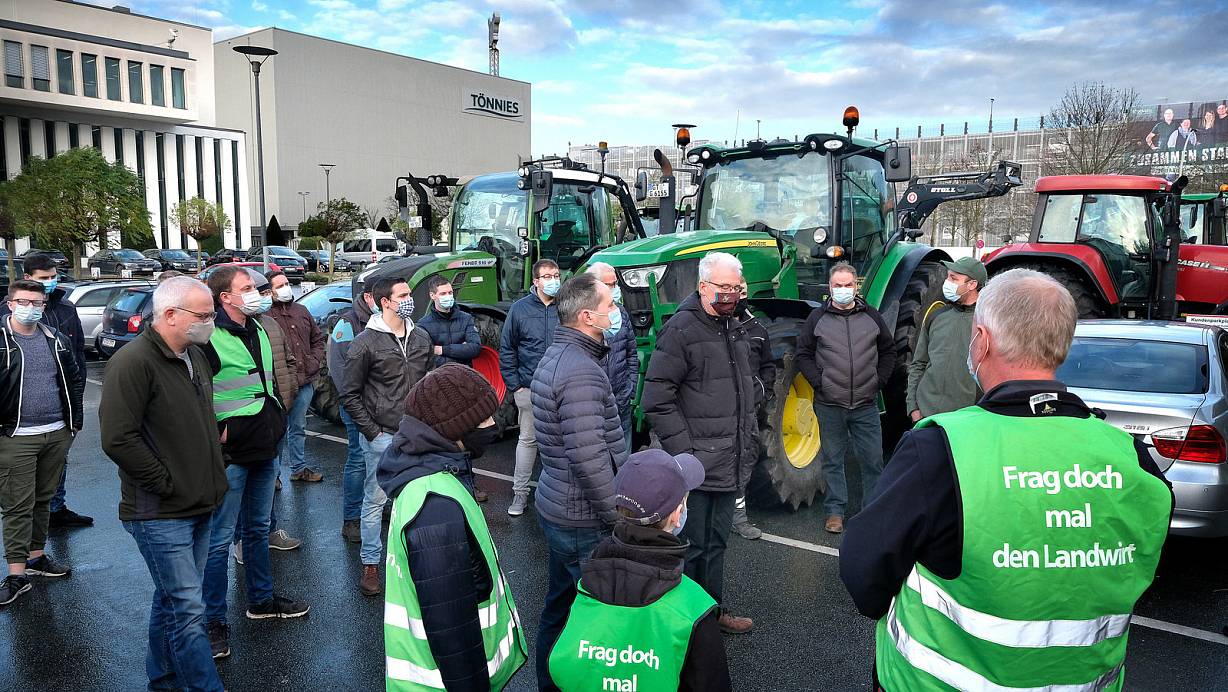 Rund 40 Landwirte äußeren ihren Unmut vor dem Fleischwerk Tönnies über die gesenkten Schweinepreise. Dass die Bauern nun noch dringlicher das Gespräch mit Verarbeiten und Handel suchen, macht Alfred Micheel mit seiner Weste deutlich. Er ist mit seinen Kindern Linus und Inga aus Ennigerloh zu der Kundgebung gekommen. | © Andreas Frücht