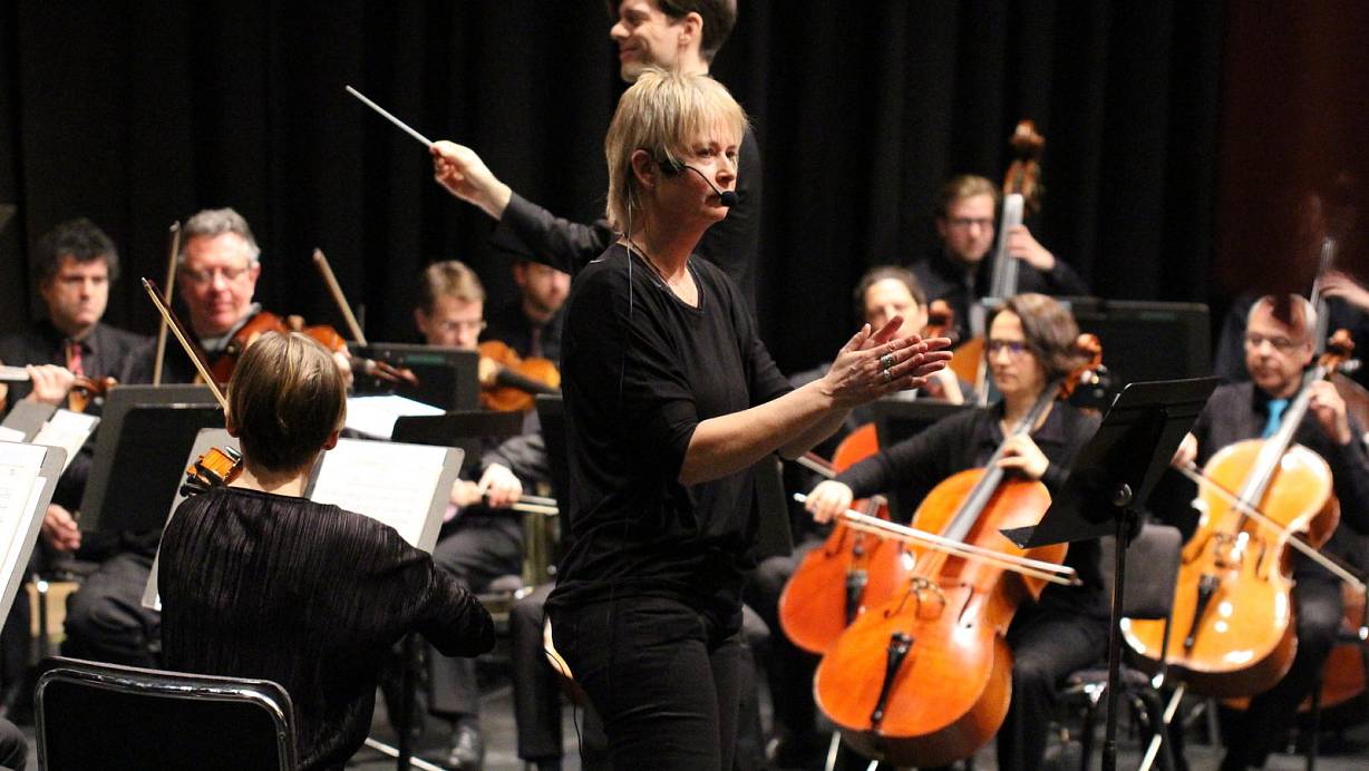 Orchester mit Dirigent Johannes Braun sowie Marion Thauern, die das Konzept für das Kinderkonzert entwickelt hat. | © Torsten Wegener