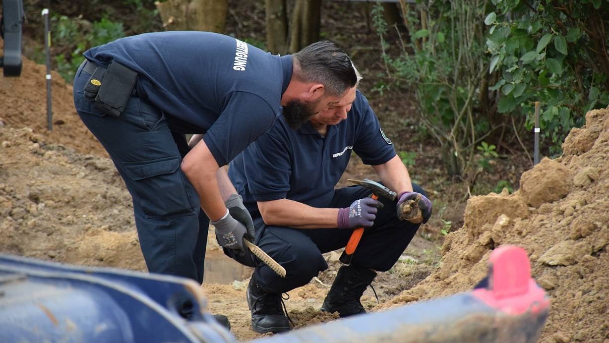 Mit vorsichtigen Hammerschlägen beseitigen die beiden Männer des Kampfmittelräumdienstes das Fundstück von Dreck. | © Ilja Regier