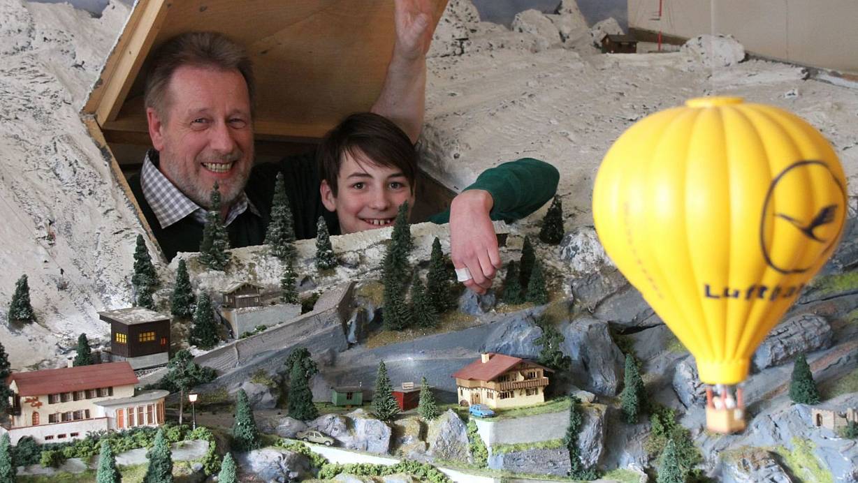 Blick durch die Luke: Klaus-Jürgen Brauner (61) und eines der jüngsten und neuesten Mitglieder, Patric Bortel (12), schauen duch diese Holzklappe und kommen so an jede Stelle der Modelleisenbahnanlage der Spur H0 im Maßstab 1 zu 87 heran. | © Johannes Wöpkemeier