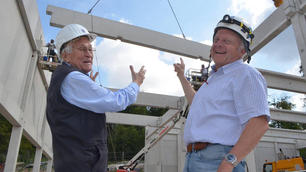 Wolfgang Soldan, ehemaliger Leiter des Betonfertigteilwerks Bielefeld (l.), und Bauleiter Achim Bokermann beobachten, wie eine Strebe für das Dach der Sporthalle heranschwebt. Foto: Sibylle Kemna | © Sibylle Kemna