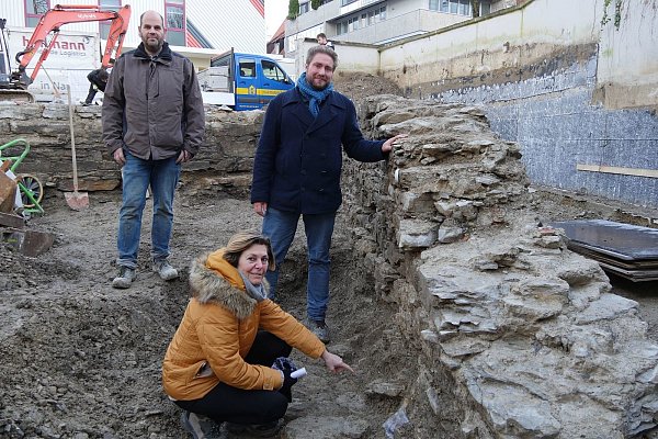 Sveva Gai (Stadtarchäologie Paderborn, LWL-Archäologie), Ralf Mahytka (Eggenstein Exca) und Till Lodemann (Stadtarchäologie Paderborn, LWL-Archäologie) präsentieren den Befund der Immunitätsmauer. - © LWL/ Christian Gobbers