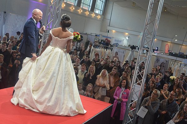 Modenschau mit Mann: Moderator Holger Mast präsentiert den vievielen Messebesuchern das Brautkleid von Model Sukanya. - © Dietmar Gröbing