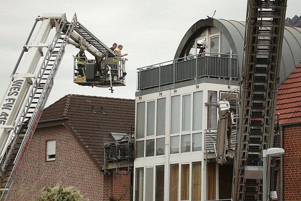 Feuerwehrleute stehen an einem beschädigten Wohnhaus auf einer Drehleiter. - © picture alliance/dpa
