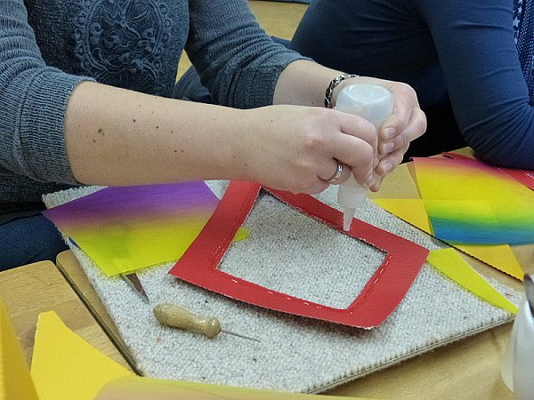 Auf das Regenbogenpapier werden ebenfalls zwei gleichgroße Rauten gemalt und ausgeschnitten. Tipp: Die Rauten etwas kleiner als die Vorherigen ausschneiden, damit sie passend auf die Rauten aus Wellpappe geklebt werden können.