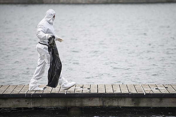 Ein Polizist trägt am Nordufer des Maschsees in Hannover eine Mülltüte, die von einem Polizeitaucher geborgen wurde. Am Tag zuvor wurden Teile einer weiblichen Leiche im Maschsee gefunden. - © FOTO: DPA