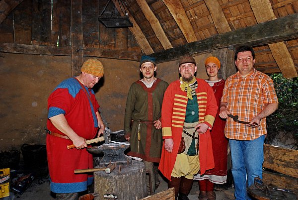 Living History: Sebastian von Nagaroon (l.) bei der Arbeit in der Schmiede. Daniel Naguschewski, Andreas Geisbüsch und Xenia Stiewe (v. l.) stellen die häusliche Arbeit des Frühmittelalters naturgetreu nach. Roeland Paardekooper ist Museumsleiter. - © Gunter Held