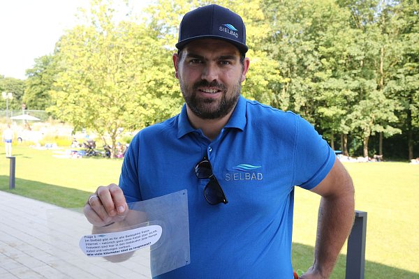 Marc Brünger hat eine der Quizfragen wasserdicht verpackt um sie auf dem Boden eines Beckens für die Taucher zu verstecken. - © Elke Niedringhaus-Haasper