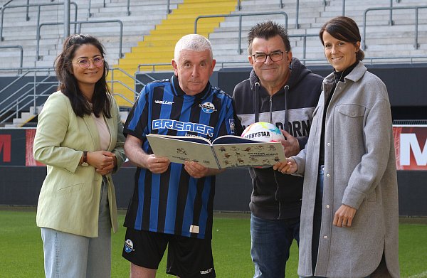 Autor Erwin Grosche (2. v. l.) sowie die SCP-Mitarbeiter Elena Palacek (l.), Martin Hornberger und Neele Rickers stöbern im Buch "Die keine Fußballschule". - © SC Paderborn 07