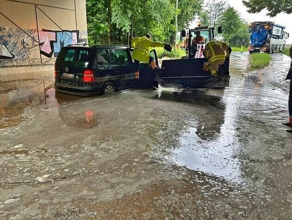 In Grevenbroich stehen ein Van und ein kleiner Frontlader nach heftigen Regenfällen auf einer überfluteten Straße. - © Feuerwehr Grevenbroich/dpa