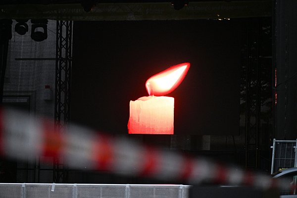 Auf einem Bildschirm einer Bühne brennt auf dem Fronhof eine Kerze. Am Freitagabend waren bei einem Stadtfest in Solingen drei Menschen mit einem Messer getötet worden. - © dpa