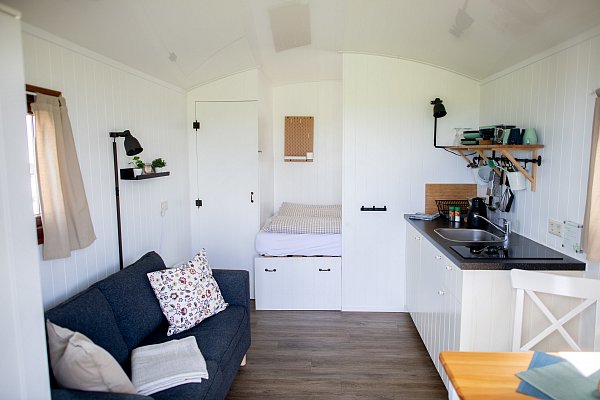 Ein Sofa, ein Bett und eine Küchenzeile sind in einem sogenannten Pipowagen auf dem Campingplatz an der Nordseeküste verbaut. - © Hauke-Christian Dittrich