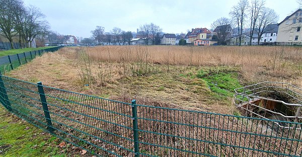 Das vor gut einem Jahrzehnt gebaute Regenrückhaltebecken am Bolbrinker in Gadderbaum (hinten die Sparrenburg) ist mittlerweile ordentlich zugewachsen, ab und zu lichtet die Stadt hier das Grün, das aber auch die Fließgeschwindigkeit abbremst. Es gibt Überlegungen, hier bei Starkregen noch mehr als die bisher möglichen vier bis fünf Millionen Liter Wasser aufzustauen. Die GTB-Tennishalle links soll abergissen werden. - © Kurt Ehmke