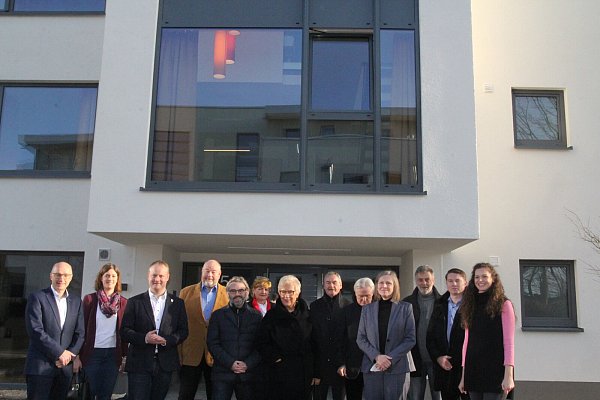 Alle Beteiligten an dem innovativen Projekt "Welcomehaus" vor dem Haupteingang zu dem viergeschossigen Gebäude mit 15 Wohnungen, zwei Gemeinschaftsräumen, Lounge-Bereich und großer Dachterrasse. - © Klaus Frensing