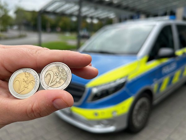 Links die Fälschung, rechts das Original: Eine Polizistin zeigt die beiden Münzen zum Vergleich. Die Nachahmung erkennt man unter anderem daran, dass auf der Vorderseite Furo statt Euro steht. - © Christian Bröder