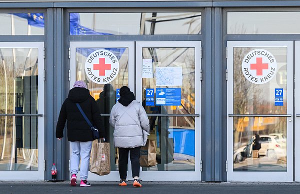 Zwei Frauen gehen in die Messehalle 27 auf der Messe Hannover. Nachdem in der Messehalle 27 bereits 1.200 Flüchtlinge aus der Ukraine untergebracht werden konnten, richtet die Stadt Hannover nun kurzfristig in einer weiteren Messehalle eine Flüchtlingsunterkunft für weitere 750 Flüchtlinge ein. - © Julian Stratenschulte/dpa