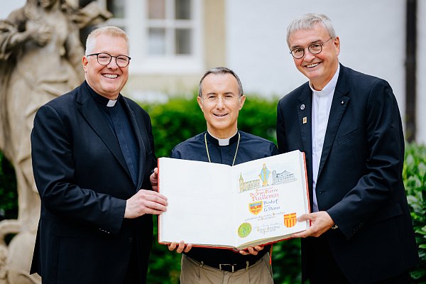 Bischof Jean-Pierre Vuillemin (Mitte), mit Diözesanadministrator Monsignore Michael Bredeck (l.) und Prälat Thomas Dornseifer, trägt sich ins Goldene Buch des Erzbistums Paderborn ein. - © BESIM MAZHIQI