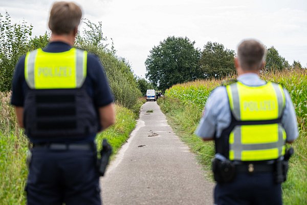 Polizeibeamte stehen am Rande des Maisfeldes, wo zwei männliche Leichen gefunden wurden. - © Guido Kirchner