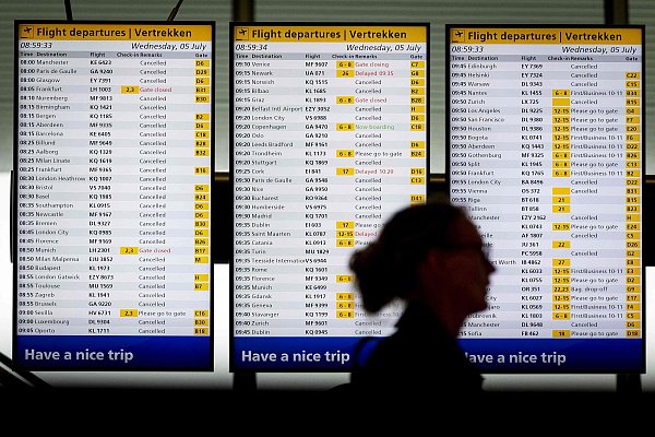 Eine Frau steht vor Fluginformationstafeln am Flughafen Schiphol in Amsterdam, 5. Juli. Starker Wind und schlechte Sicht aufgrund von Regen zwangen die KLM Royal Dutch Airlines, 207 Flüge zu stornieren. - © AFP