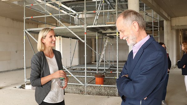 Verwaltungsmitarbeiterin und Architektin Peggy Balke erklärte bei einem Rundgang durch den Rohbau, was in dem Anbau alles untergebracht ist. Hier steht sie zusammen mit Schulleiter Manfred Kurtz vor dem Innenhof im Untergeschoss. Im Erdgeschoss ist der Bereich durch bodentiefe Fenster von den Fluren abgetrennt. - © Birgit Guhlke