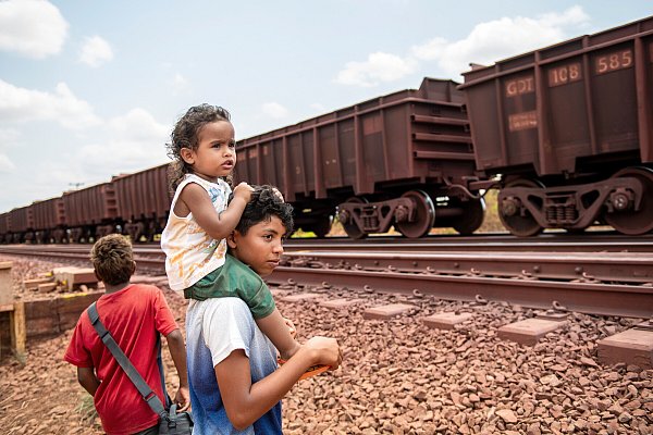Kinder schauen hinter einem vorbeifahrenden Gueterzug auf den Schienen der Bahnlinie Ferrovia de Carajas in Brasilien her. - © epd-bild / Florian Kopp