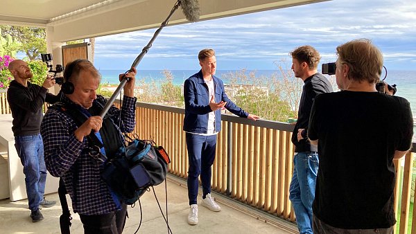 Marc-André ter Stegen wird auf dem Balkon seinen Hauses in Barcelona von Tommi Schmitt interviewt. Um sie herum stehen Teammitglieder von Kamera und Ton. - © ZDF und Gruppe 5