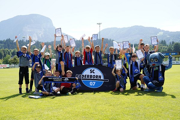 Diese Nachwuchskicker des SV Kirchbichl absolvierten auf Einladung des SC Paderborn das "Bundesliga bewegt"-Programm und reckten anschließend ihre Urkunden in die Höhe. Das freute auch SCP-Maskottchen Holli (r.). - © SC Paderborn 07/Michael Bieckmann