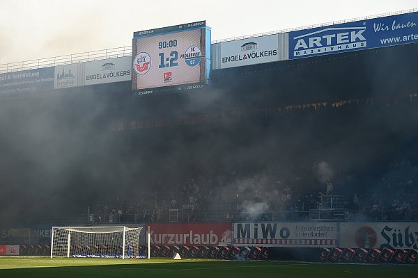 Schwarzer Rauch ist über der Südtribüne des Rostocker Ostseestadions zu sehen, nachdem Hansa-Fans Feuerwerk und Böller geworfen haben. - © Gregor Fischer / dpa