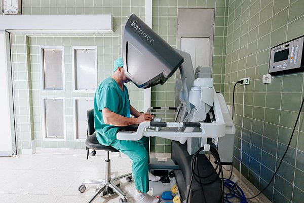 Anders als sonst sitzt der Chirurg etwas abseits vom Patienten und steuert den Roboter über eine Konsole. - © BESIM MAZHIQI