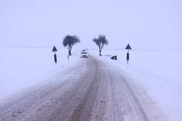 Autos fahren am Donnerstag auf einer verschneiten Landstraße bei Weilerswist in NRW. - © David Young / dpa