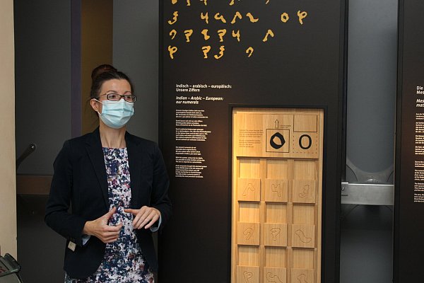 HNF-Kuratorin Evelin Thomik vor einer der neuen Stelen im Eingangsbereich der Dauerausstellung. Weil zurzeit das Tragen einer medizinischen Maske im Museum verpflichtend ist, wurde darauf auch auf dem Foto nicht verzichtet. - © Sebastian Beeg