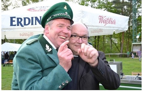 Pfarrer Karl-Joses Auris (r.) gratuliert dem neuen Schützenkönig Michael Schniedermann und jubelt mit ihm gemeinsam. Als Geste der Freude strecken sie vor den anderen Schützen und Gratulanten die Hände in die Luft. - © FOTO: CHRISTIAN STOLZ