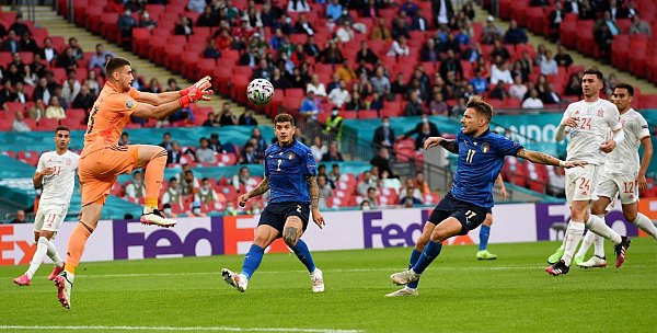 Spaniens Torwart Unai Simon (l) fängt den Ball vor Italien-Torjäger Ciro Immobile (3.v.r). - © Andy Rain/Pool EPA/AP/dpa