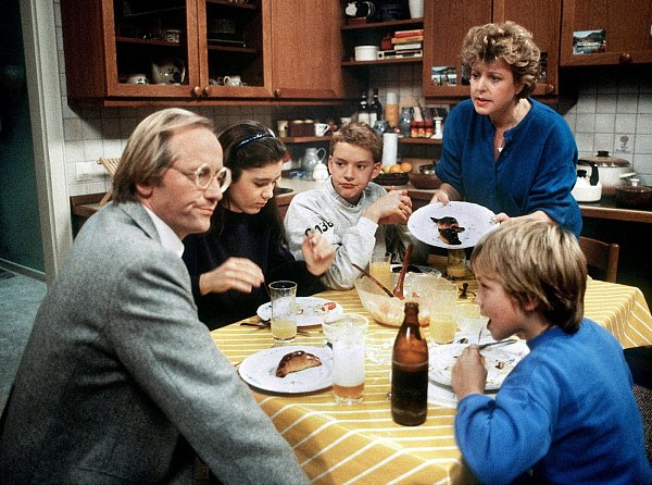 Die Urform der Beimers: Helga Beimer (Marie-Luise Marjan, hinten r.) mit ihrem ersten Mann Hans (Joachim Hermann Luger, l.) und ihren Kindern (v. l. Marion (Ina Bleiweiß), Benny (Christian Kahrmann) und Klausi (Moritz A. Sachs) in einer Szene der TV-Serie "Lindenstraße" aus dem Jahr 1986 (undatierte Aufnahme). - © Foto: WDR/dpa
